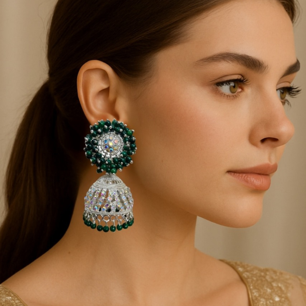 Woman wearing a pair of green and silver earrings with a neutral background