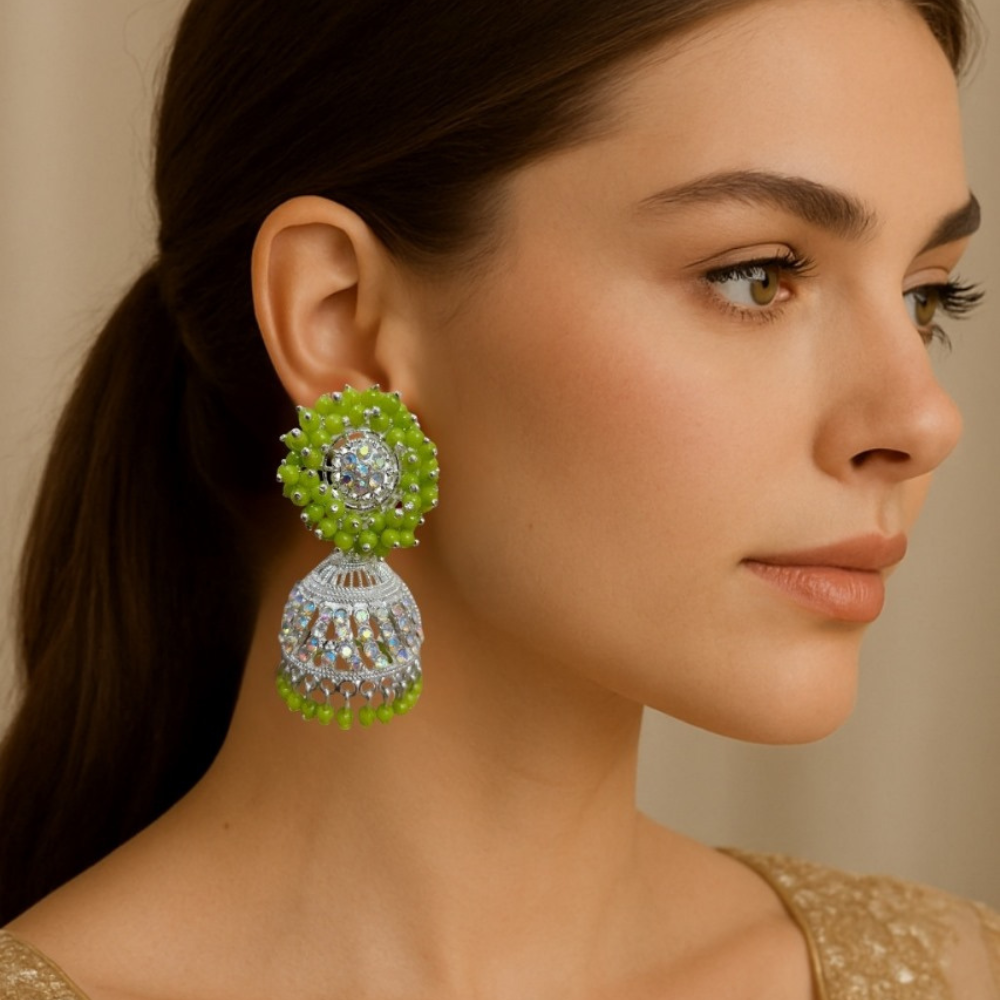 Woman wearing green and silver earrings against a neutral background