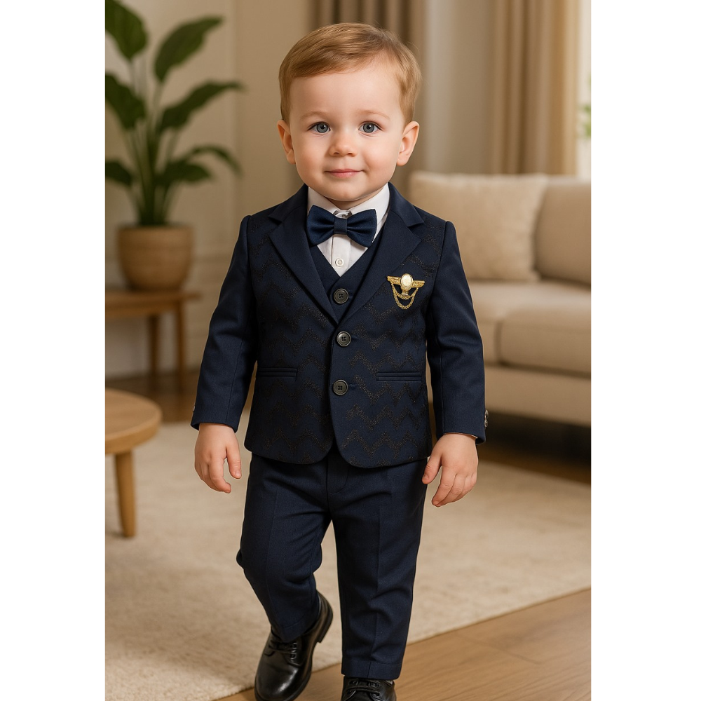 Young boy in a formal navy suit with a bow tie standing in a living room.