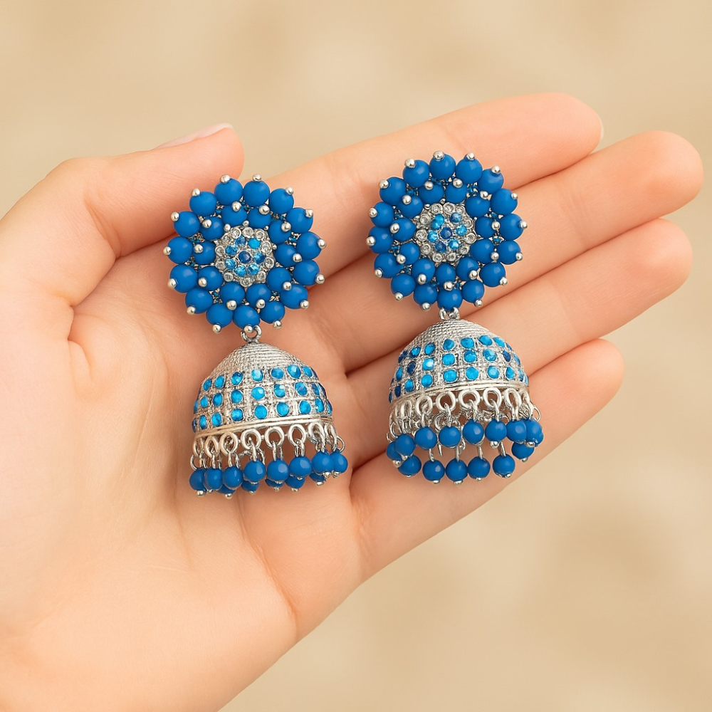 Woman wearing blue beaded earrings with a plain background