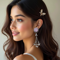 Woman wearing a decorative earring with a pink gem and star-shaped elements.