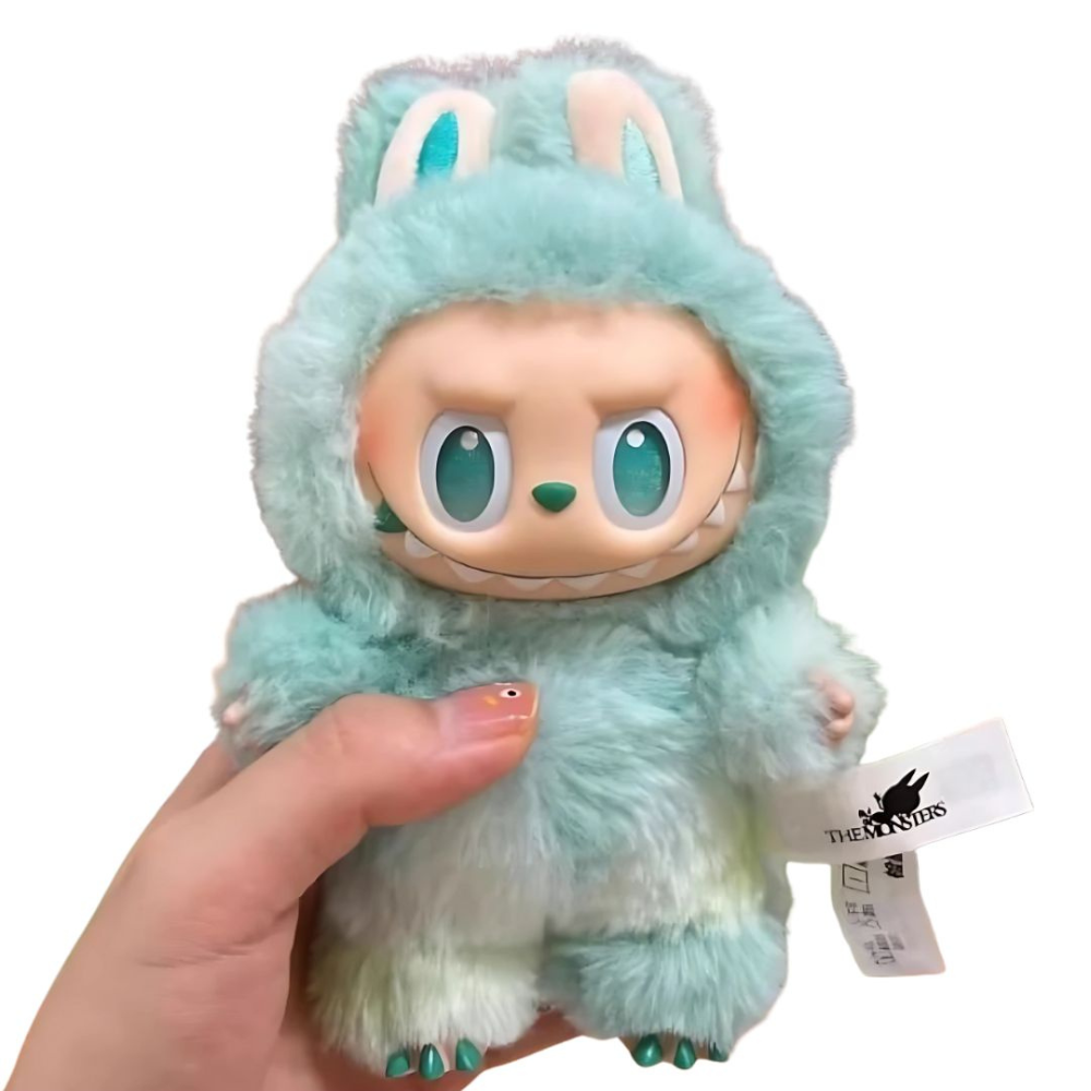 Plush toy with a hood held by a hand, brand tag visible